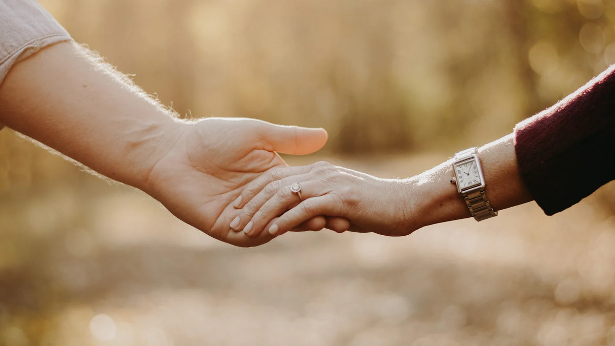 Two adults holding hands outdoors, photographed close up.