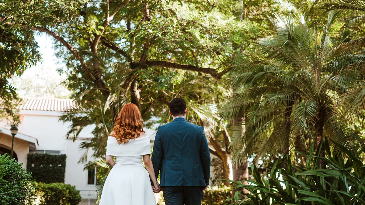 An adult couple seen from behind walking along a leafy path.