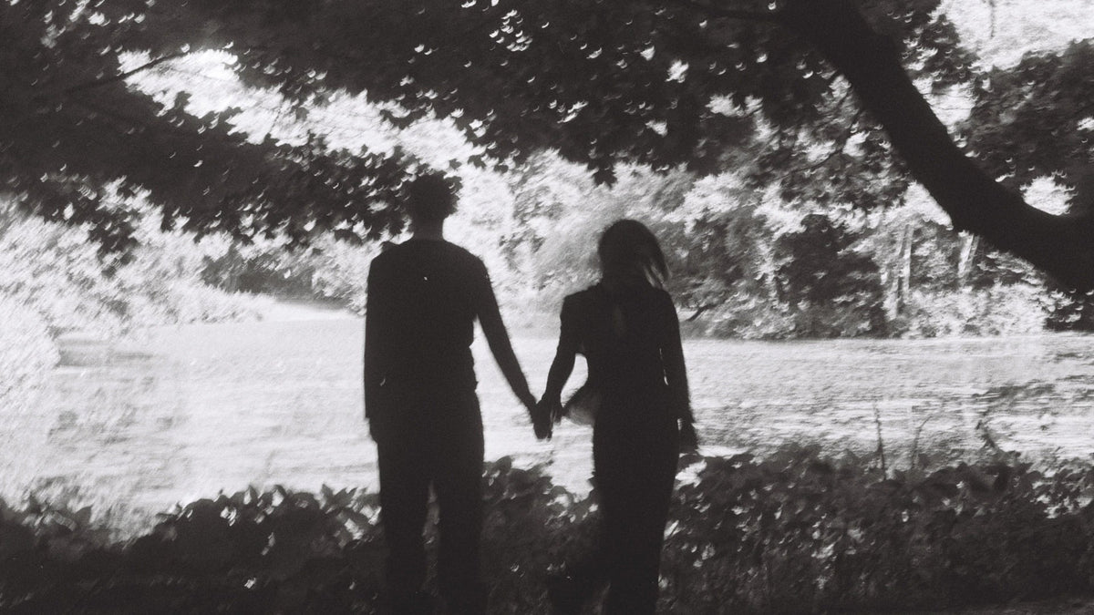 Two adults beneath a large tree in a black-and-white photograph.