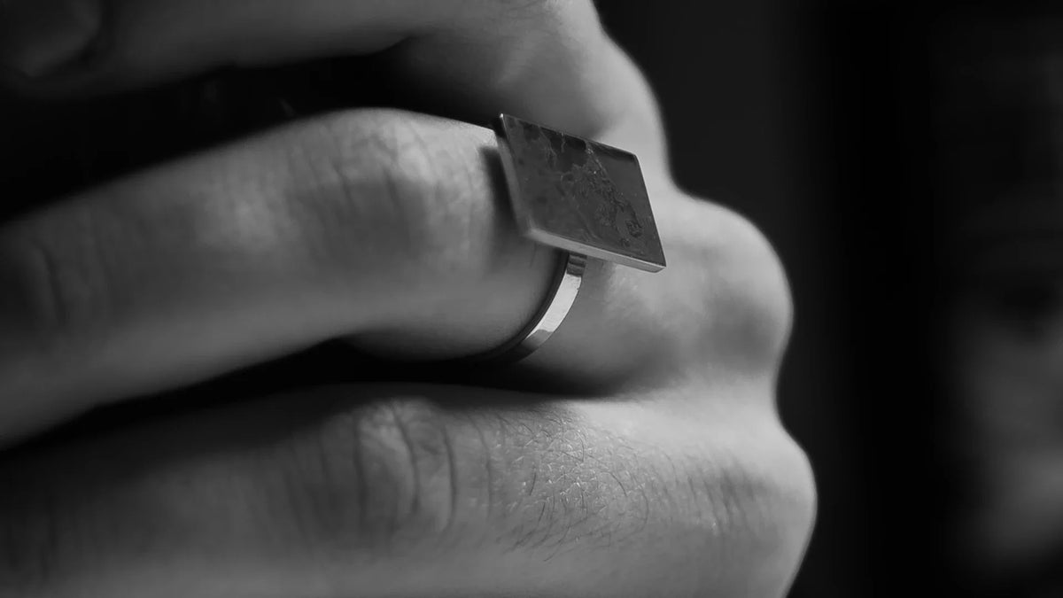 A black-and-white close-up of hands wearing a ring.