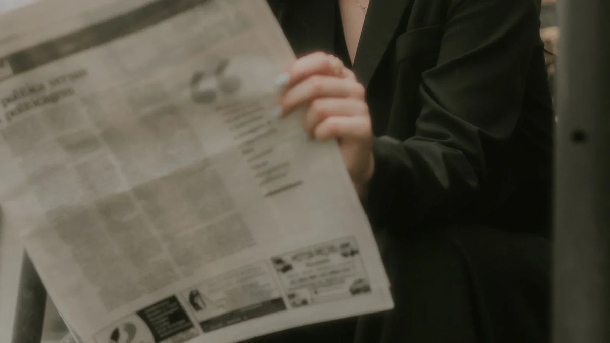 Hands hold an open newspaper.