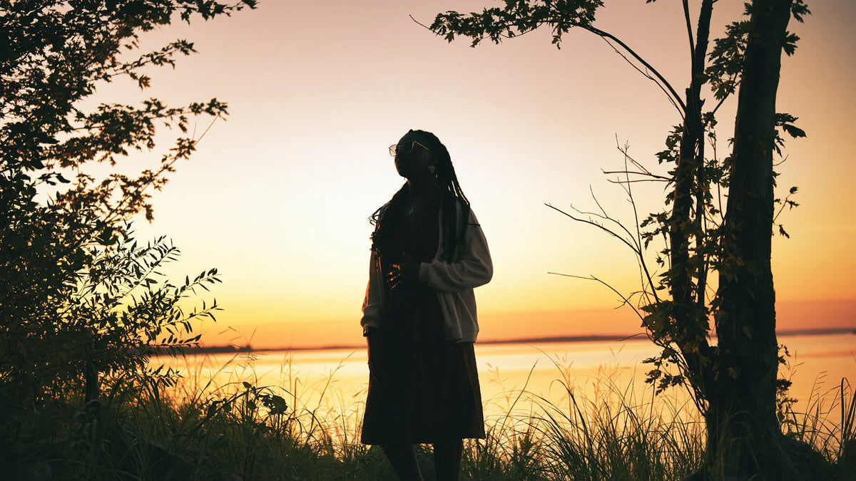 An adult woman silhouetted in an outdoor landscape.
