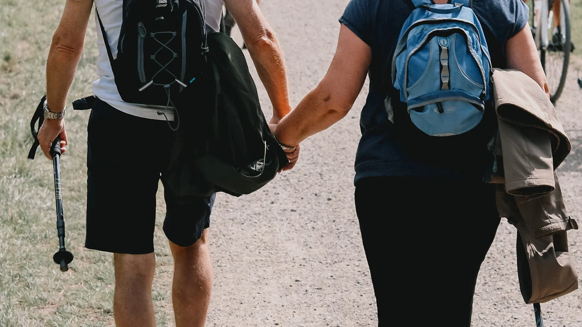 Adult companions viewed from behind while walking outdoors.