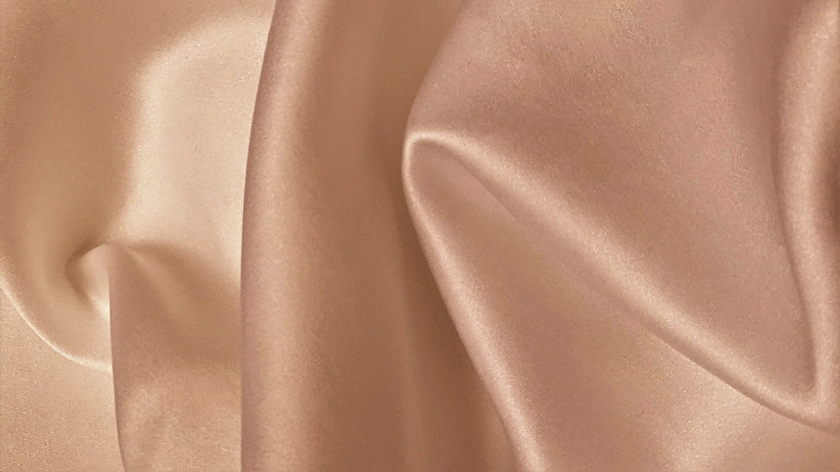Smooth rose-gold silk with softly lit folds.