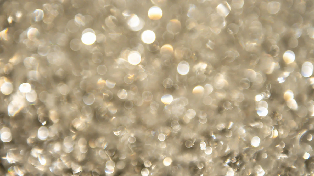 Soft-focus droplets catching light against a pale background.