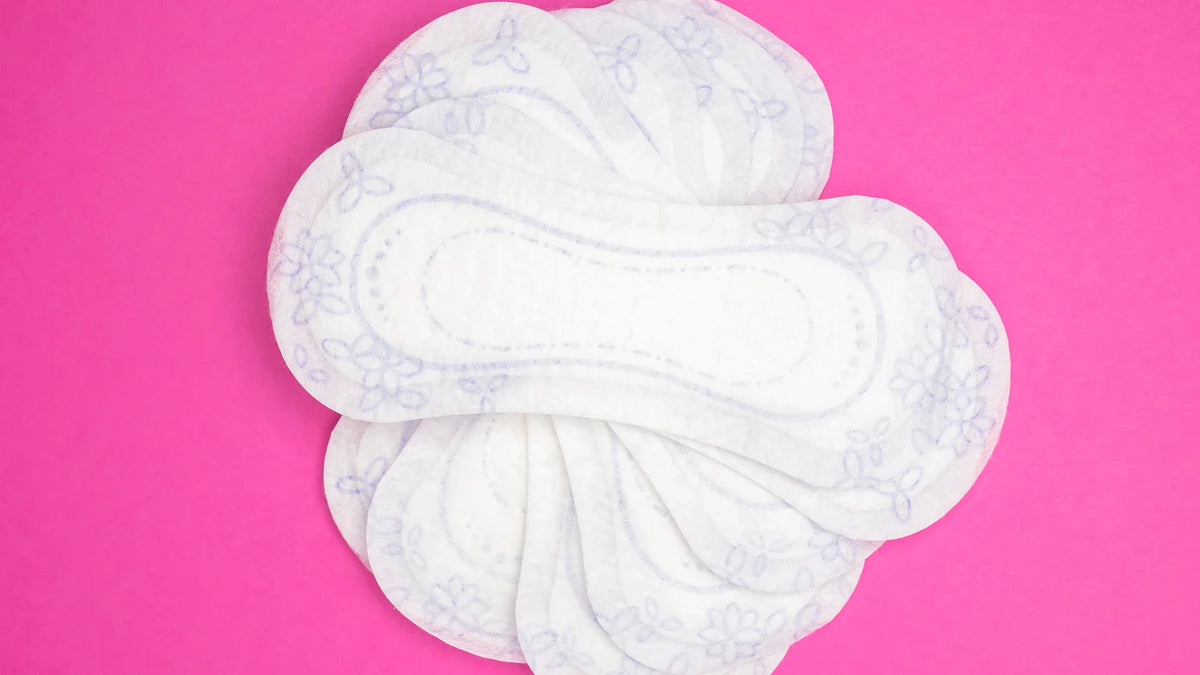 Reusable menstrual pads arranged on a bright pink background.