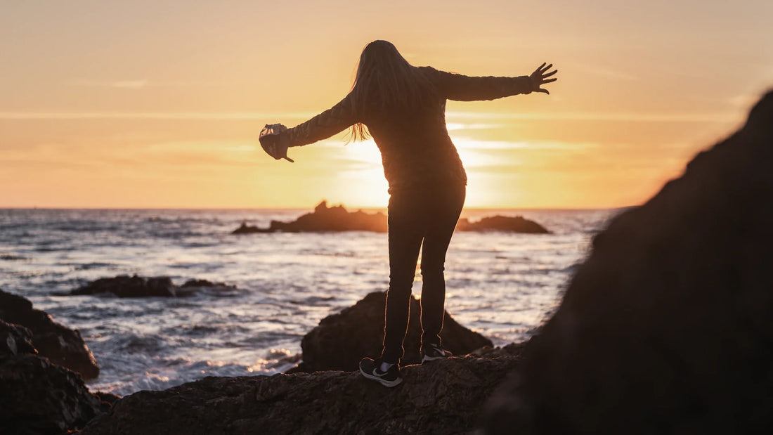 An adult woman silhouetted in an outdoor landscape.