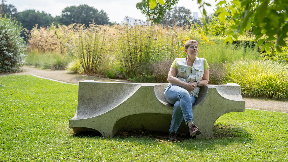 A woman sits on a bench in a park.