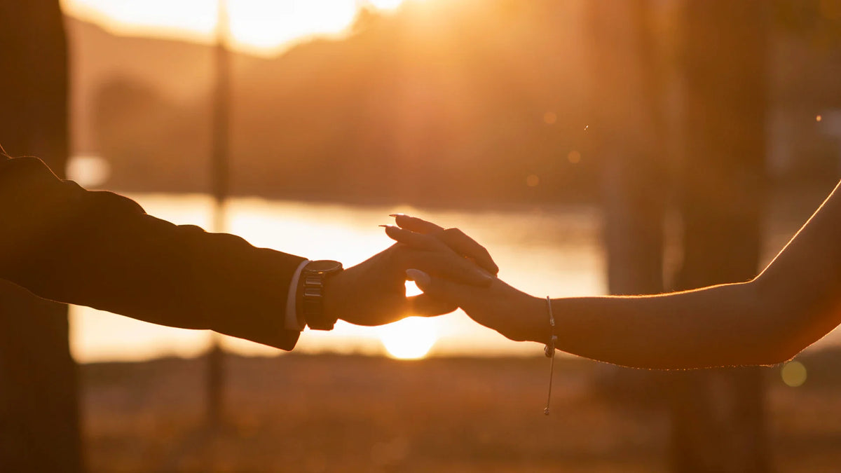 Adult companions holding hands outdoors.