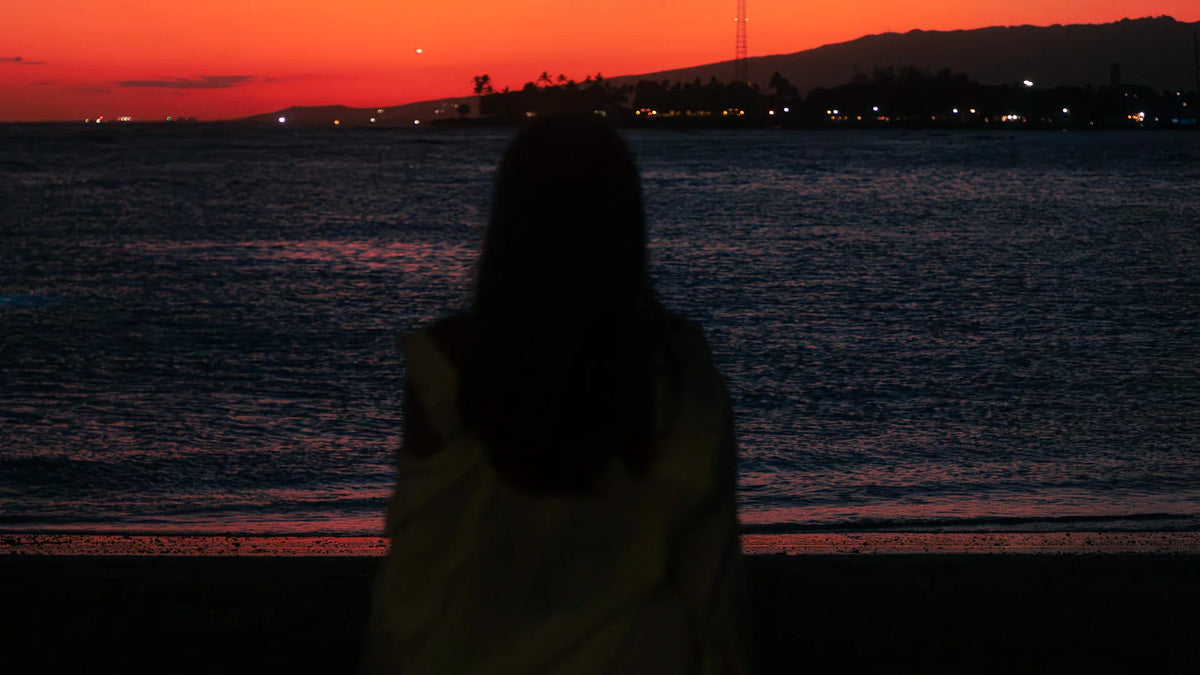 An adult woman silhouetted in an outdoor landscape.