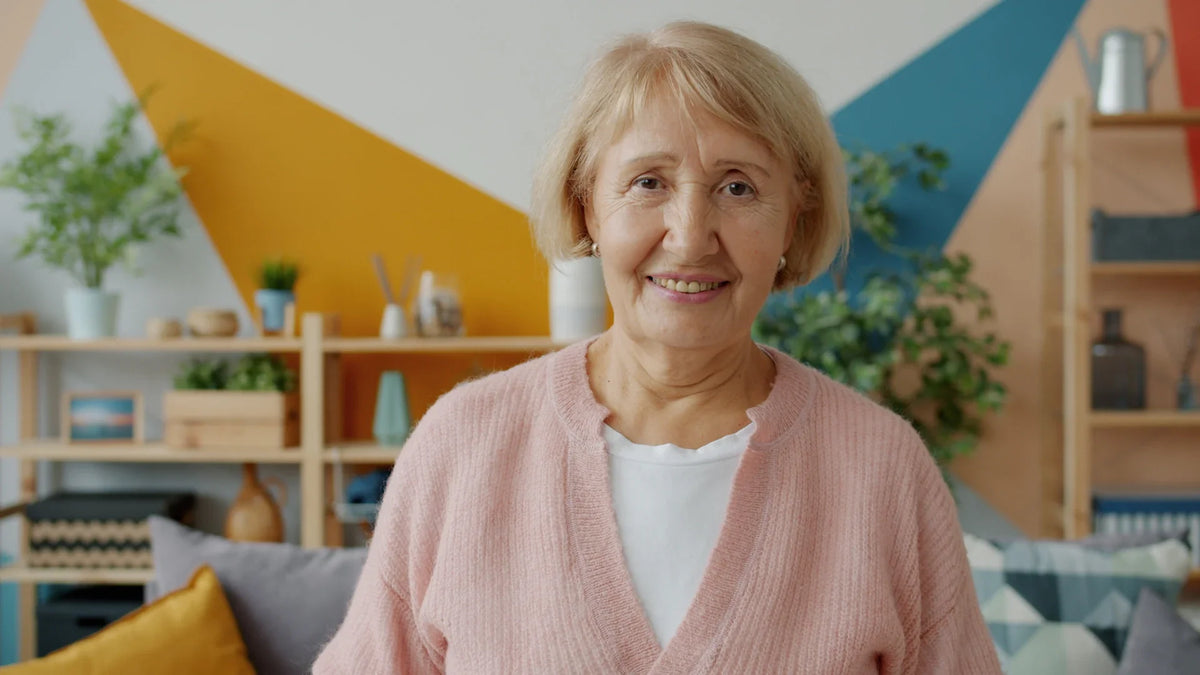 An older woman smiles in a living room.