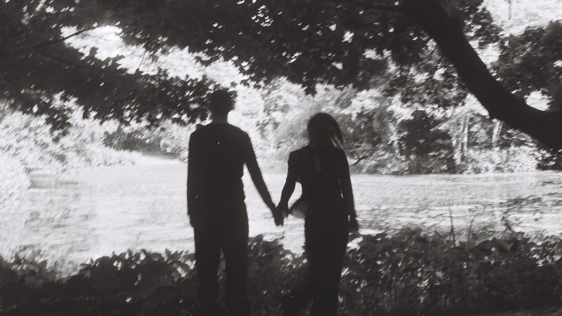 Two adults beneath a large tree in a black-and-white photograph.