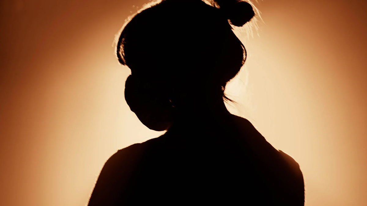 An adult woman silhouetted in an outdoor landscape.