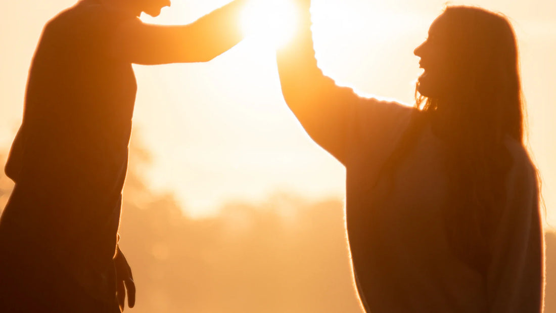 Two adults sharing a high-five in silhouette at sunset.