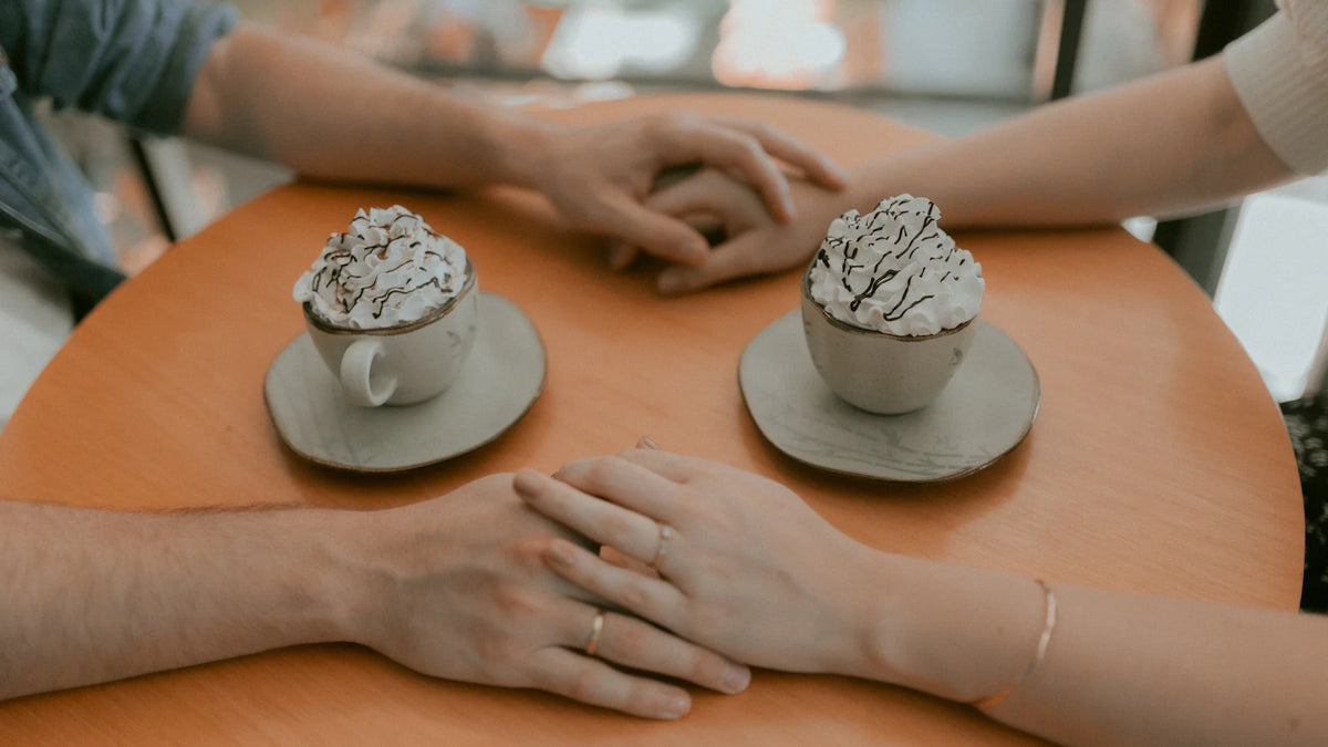 Two hands rest together over a cafe table.