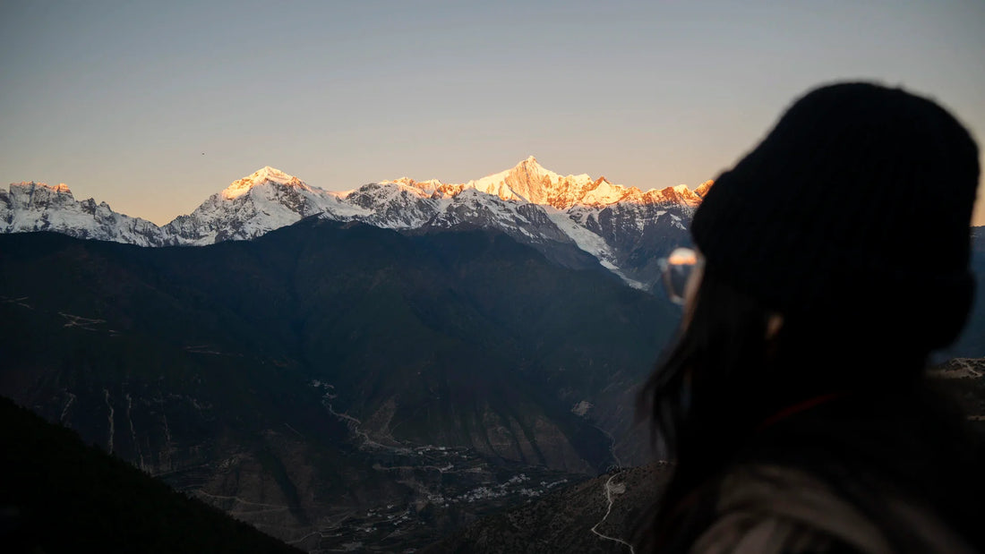 An adult woman viewed from behind in a mountain landscape.