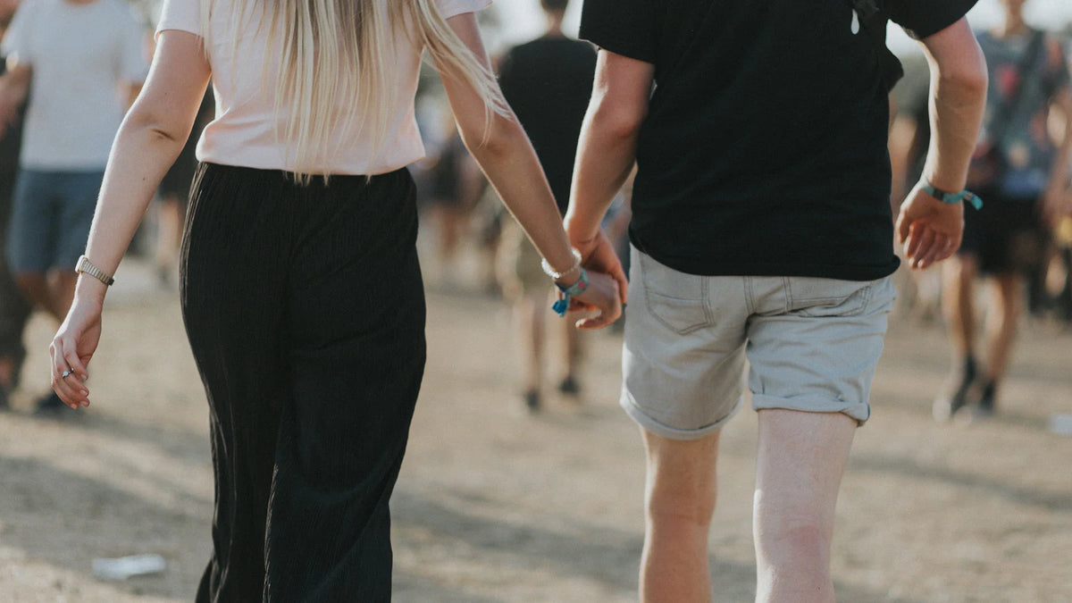 Two people hold hands while walking, with faces outside the frame.