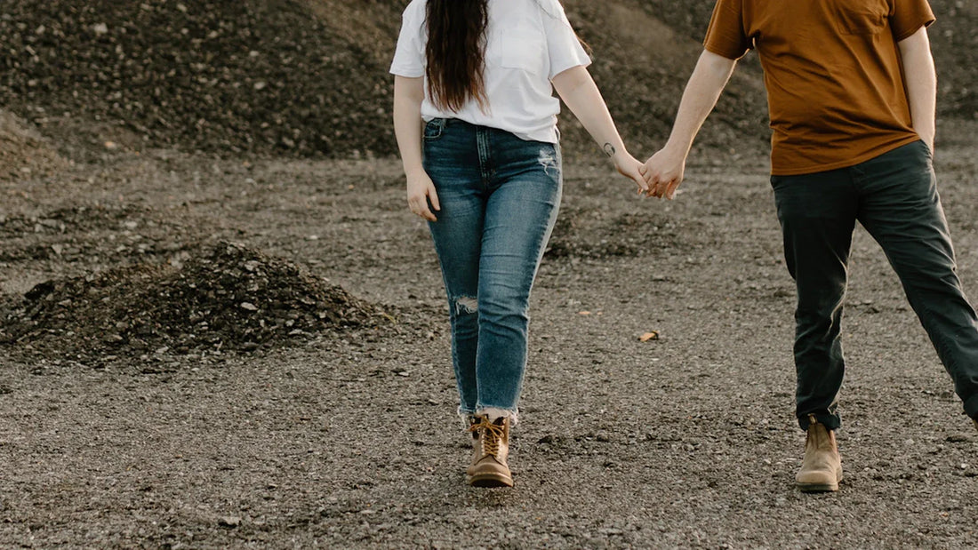 Cropped view of adult companions holding hands while walking outdoors.