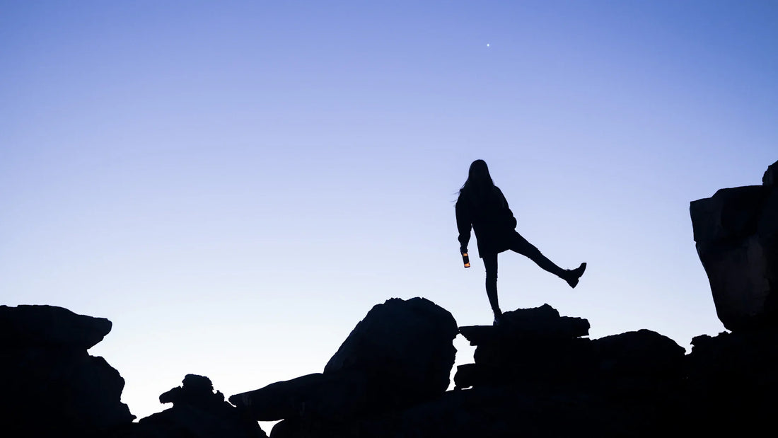 An adult woman silhouetted in an outdoor landscape.
