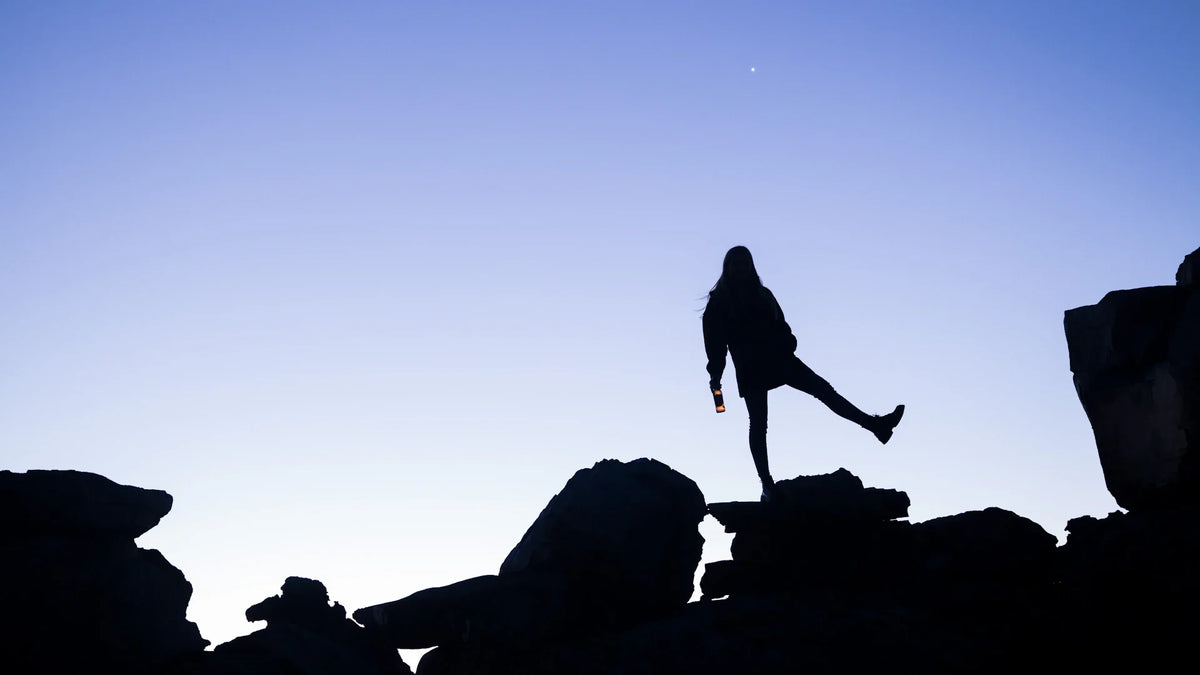 An adult woman silhouetted in an outdoor landscape.