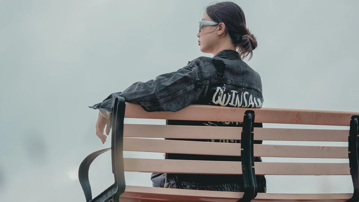 A woman sits on a park bench looking into the distance.