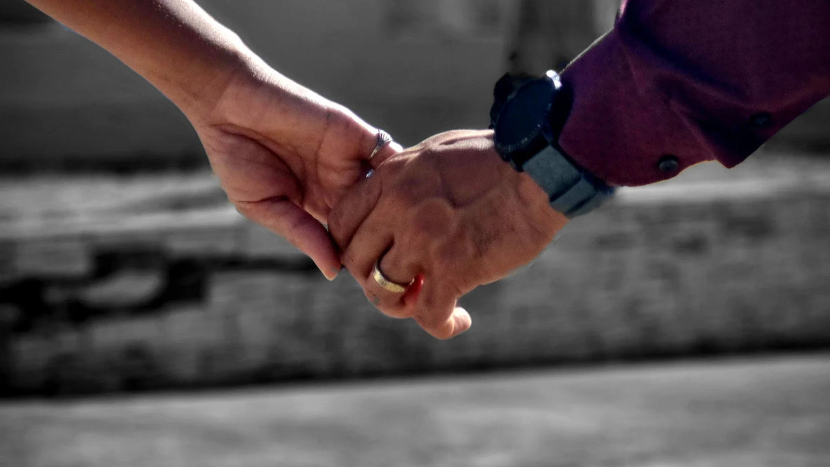 Two adults holding hands while walking outdoors.