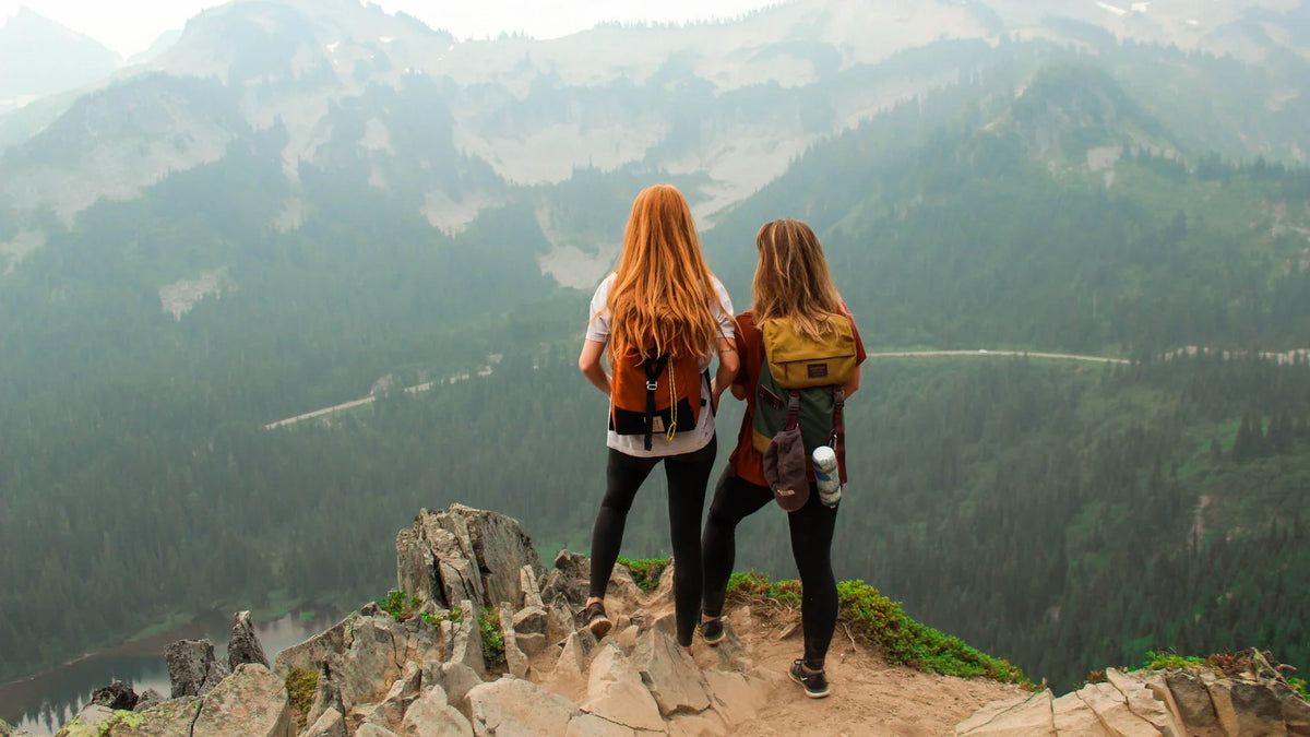 Two adult women seen from behind overlooking a mountain lake.