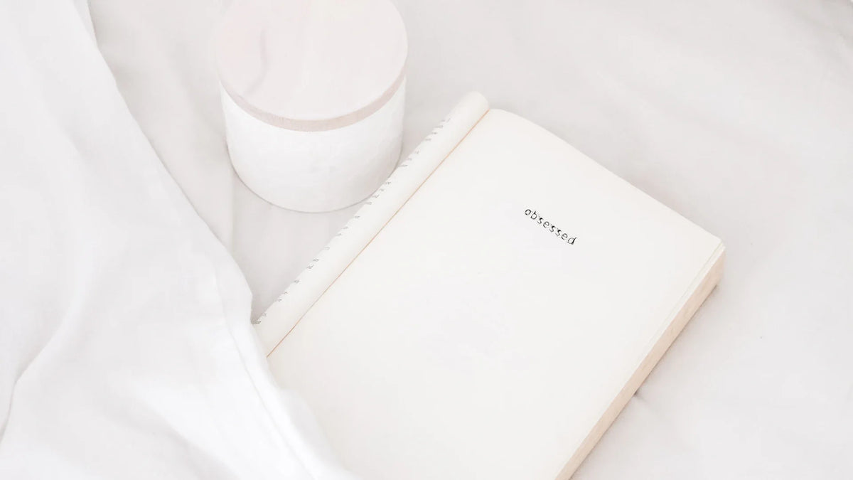An open notebook beside a coffee cup on a light surface.