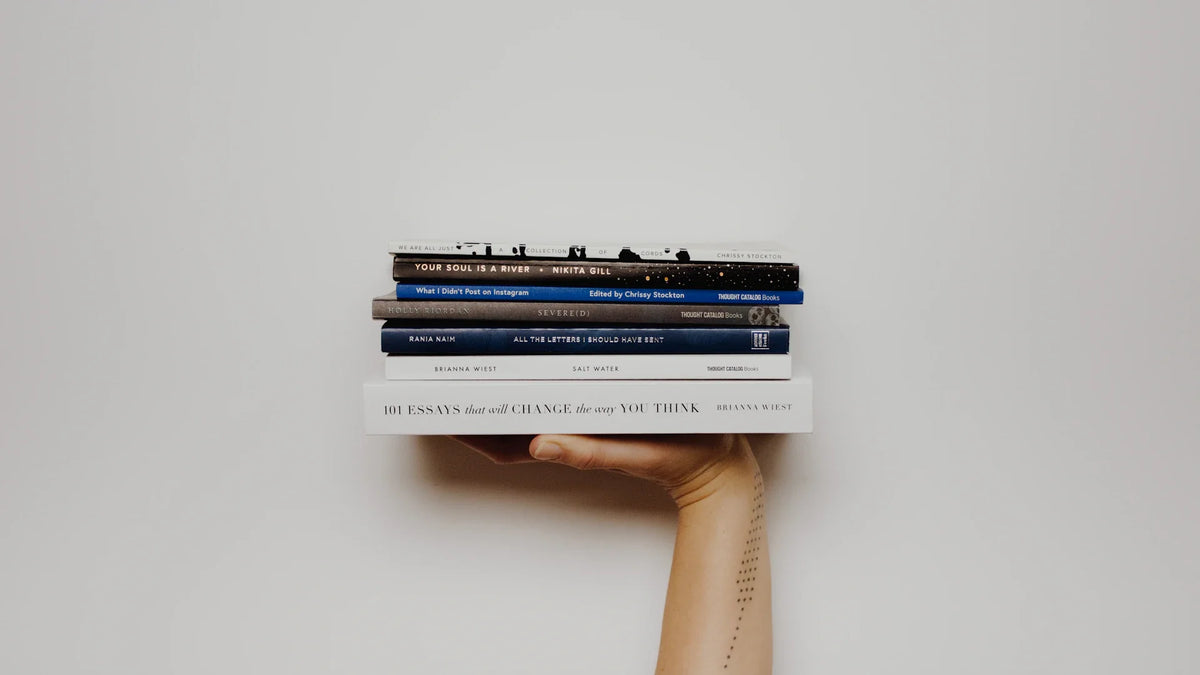 Hands hold a stack of books.