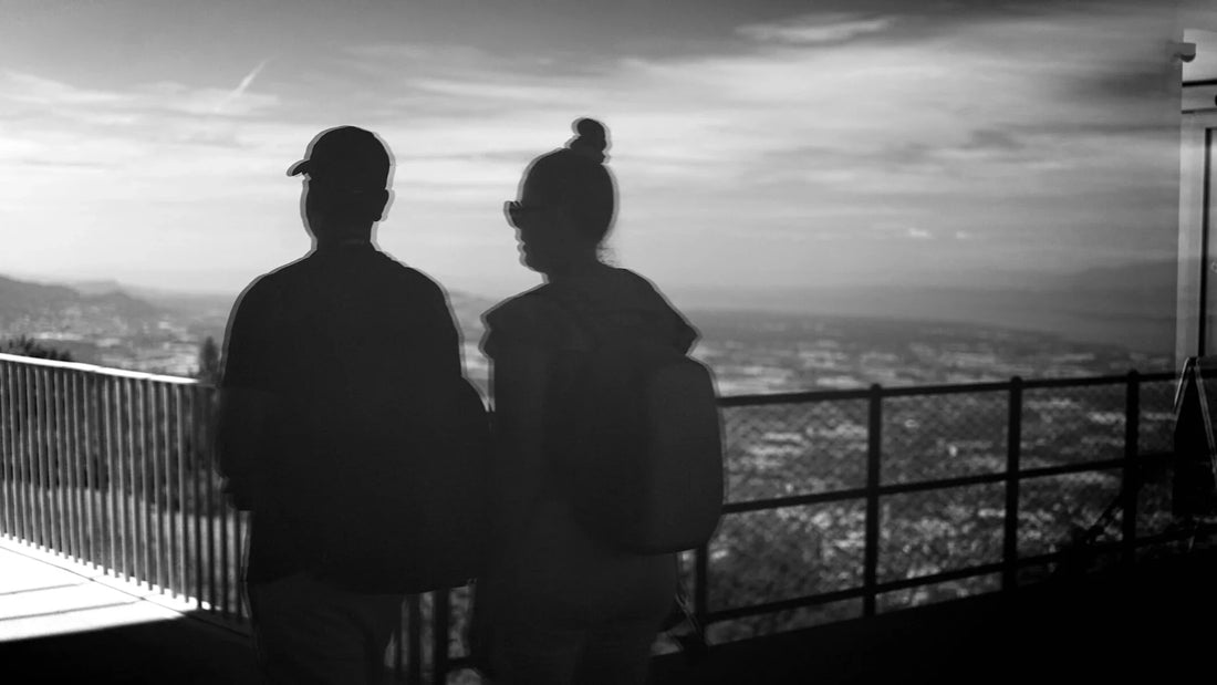Two adults’ shadows overlooking a city from a railing.