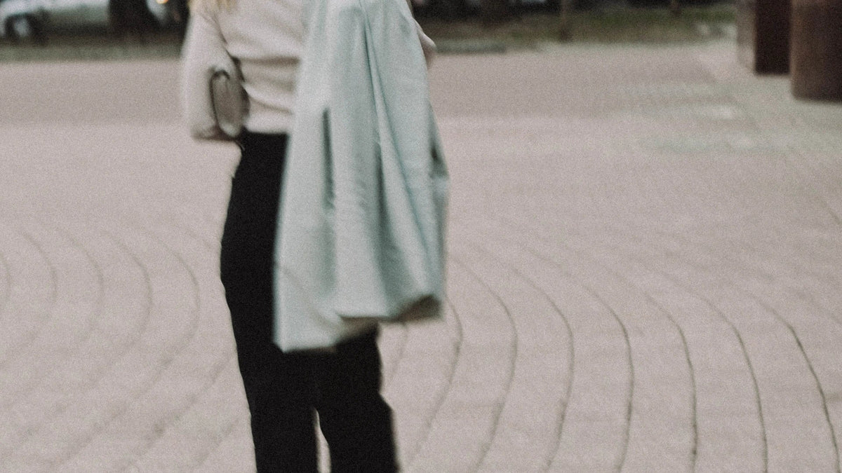 A cropped adult figure walking away with a coat over one shoulder.