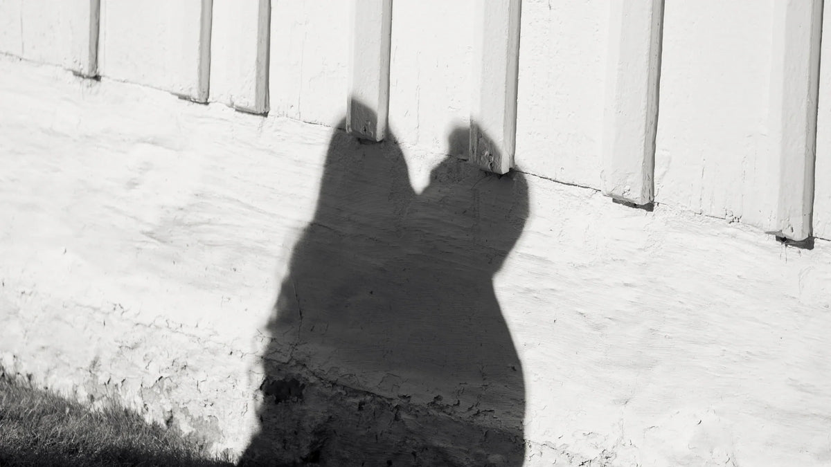 Two adults’ shadows falling on a pale outdoor wall.