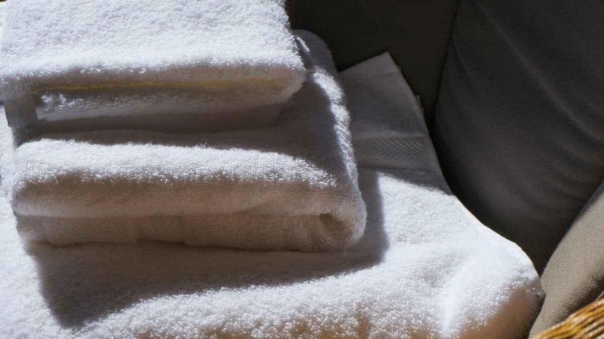 Folded white towels resting in natural sunlight.