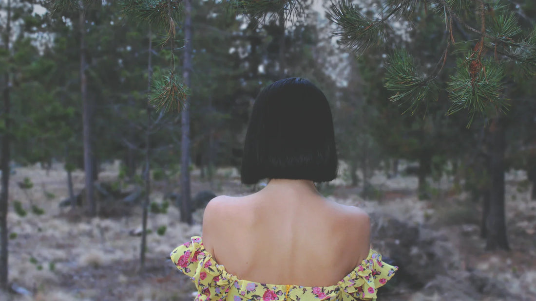 A woman seen from behind among trees.