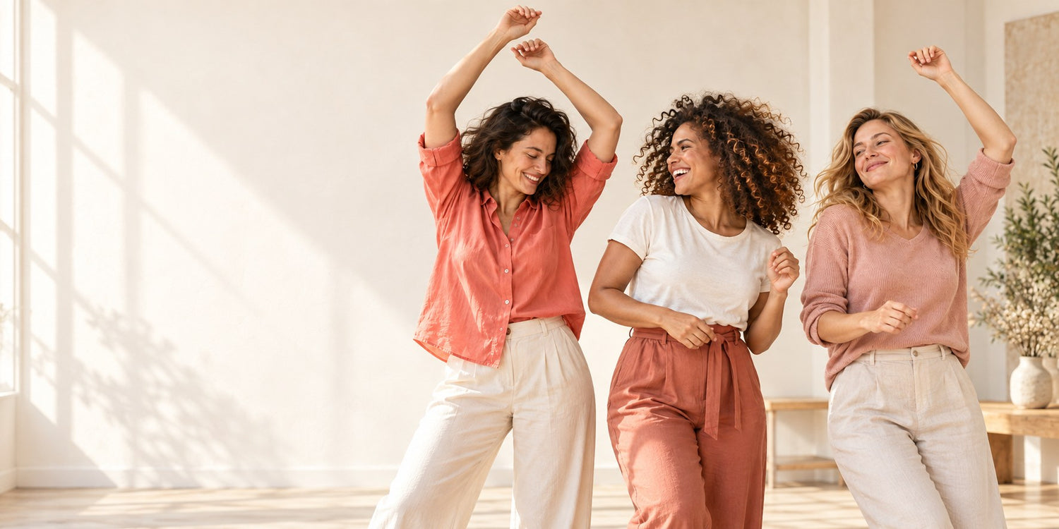 Three women dancing together in a bright sunlit room